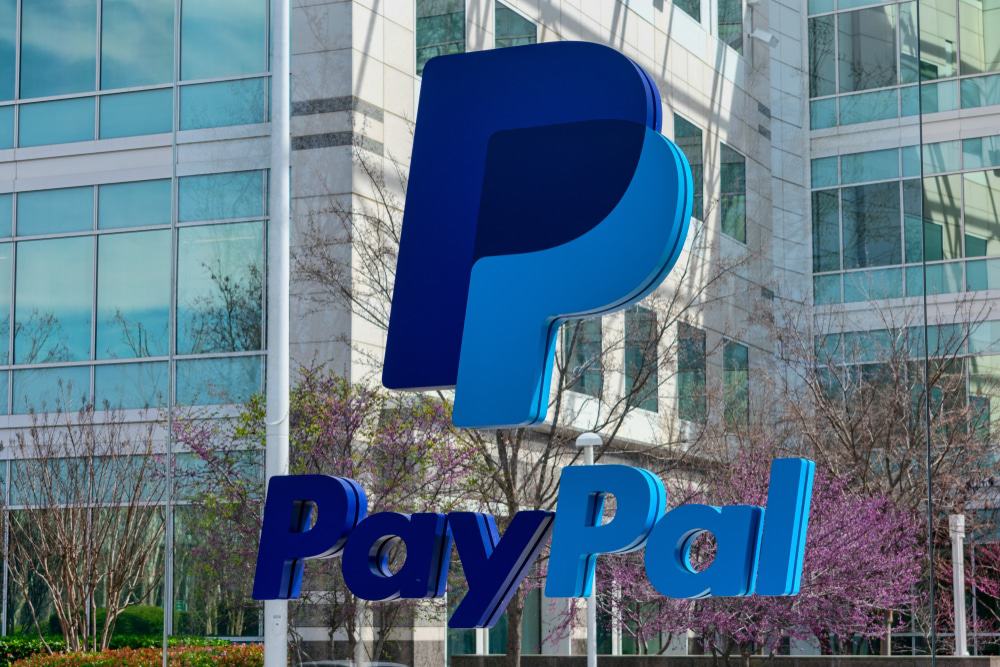 Google e PayPal se unem para impulsionar compras via IA O PayPal anunciou uma parceria plurianual com o Google para desenvolver novas experiências de compra baseadas em inteligência artificial. Logotipo do PayPal em frente ao prédio da sede da PayPal Holdings