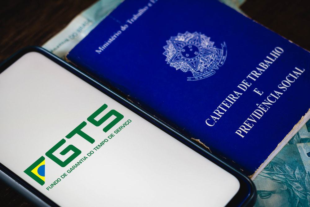 Logotipo do Fundo de Garantia do Tempo de Serviço (FGTS) é visto em um smartphone ao lado da Carteira de Trabalho e Previdência Social do Brasil