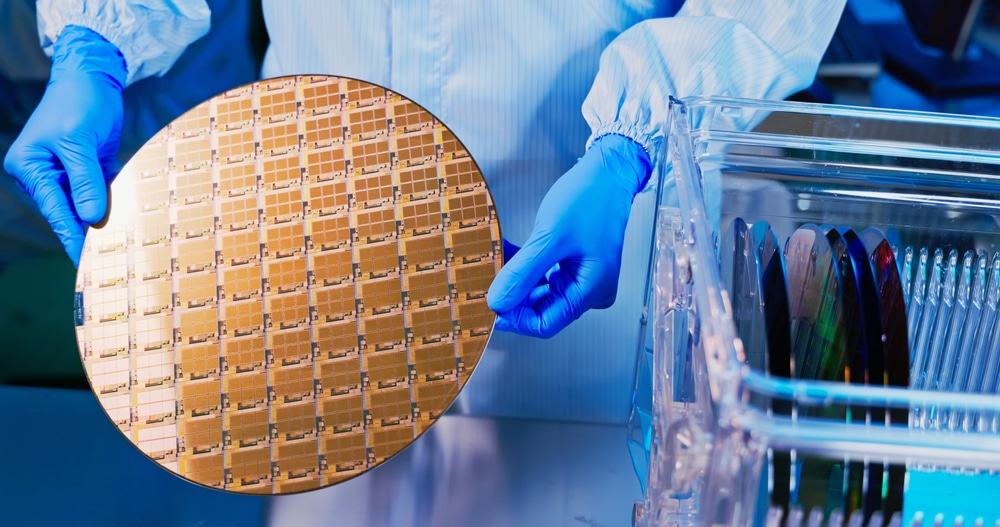 Profissional usando macacão segurando uma pastilha ou wafer de silício com luvas, ilustrando o processo de fabricação de chips ou semicondutores