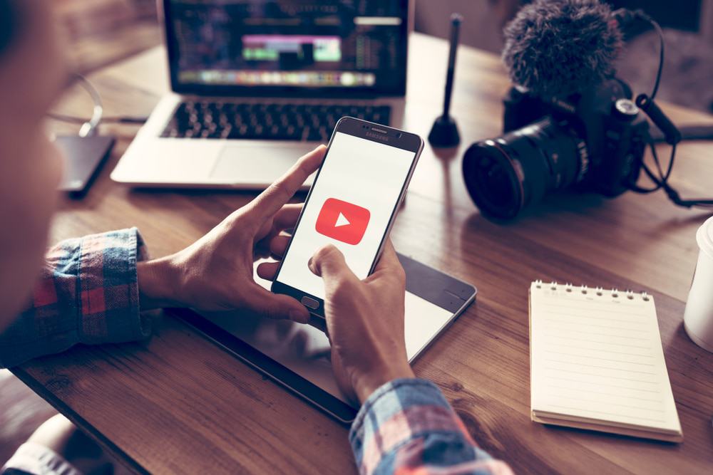 Criador de conteúdo acessando o YouTube pelo celular.