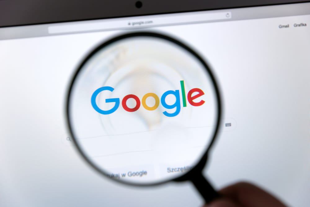 Logotipo do Google exibido através de uma lupa. O Google é o motor de buscas mais popular do mercado.