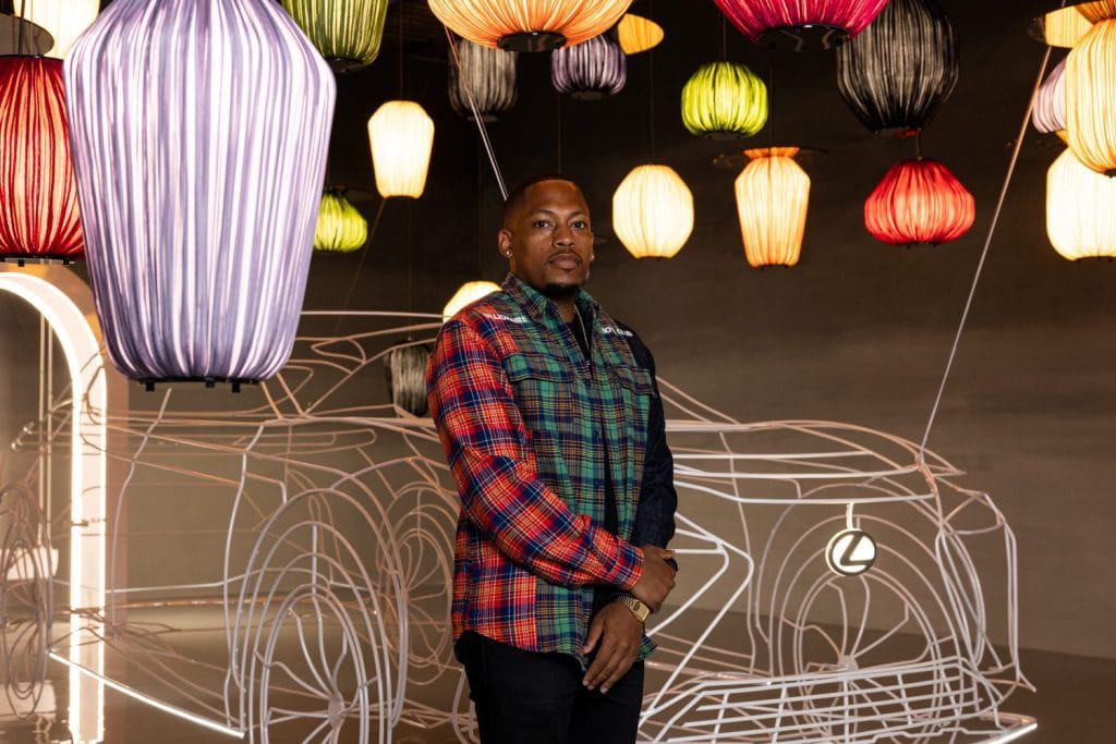 O designer americano Germane Barnes junto à sua obra artística na exposição da Lexus