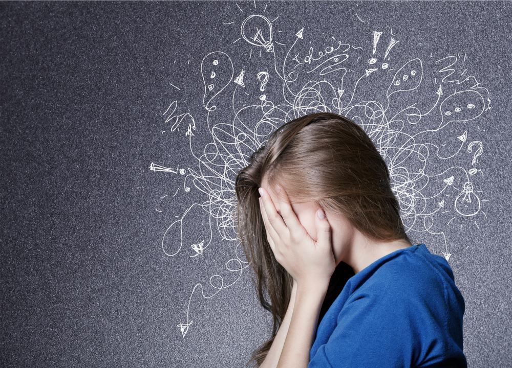 mulher tampando o rosto com desenhos representando seus pensamentos