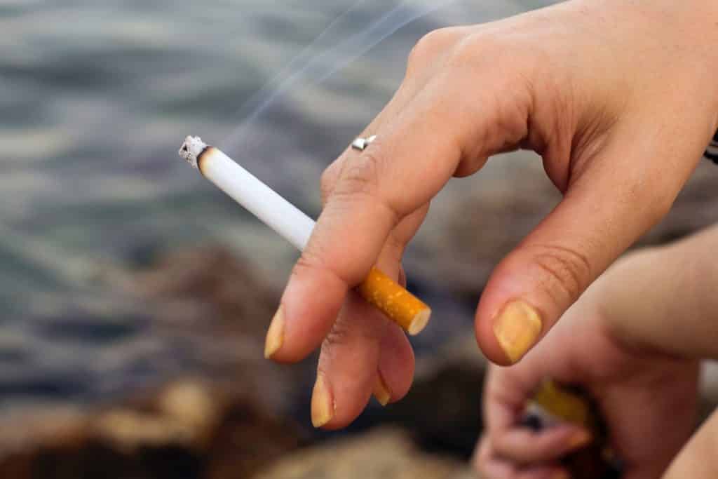 Mão de uma pessoa fumante com a ponta dos dedos amarelas