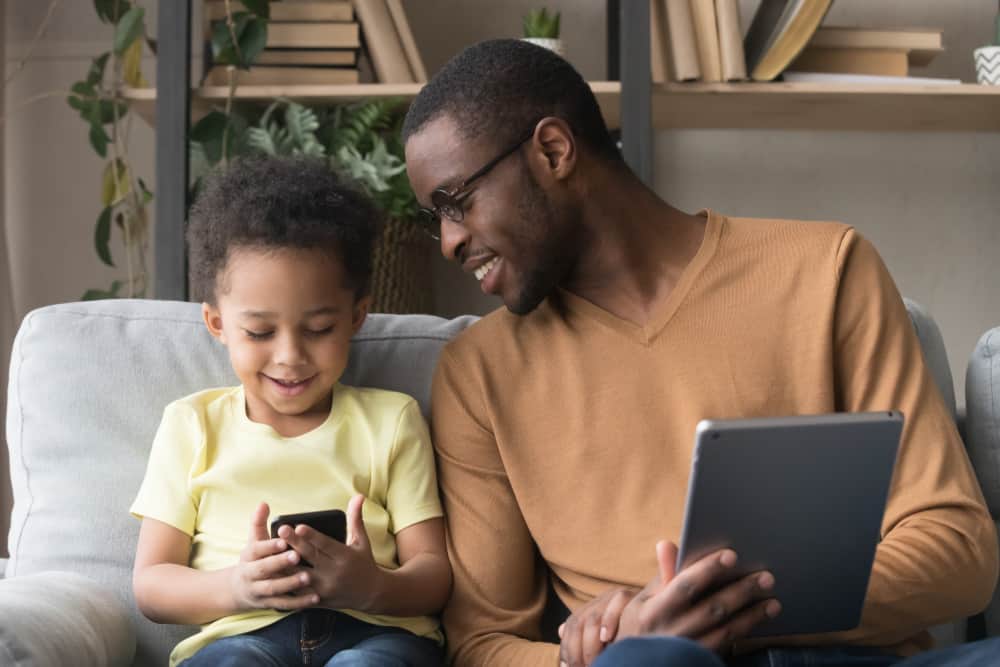 Pais e filho sentados mexendo em celulares