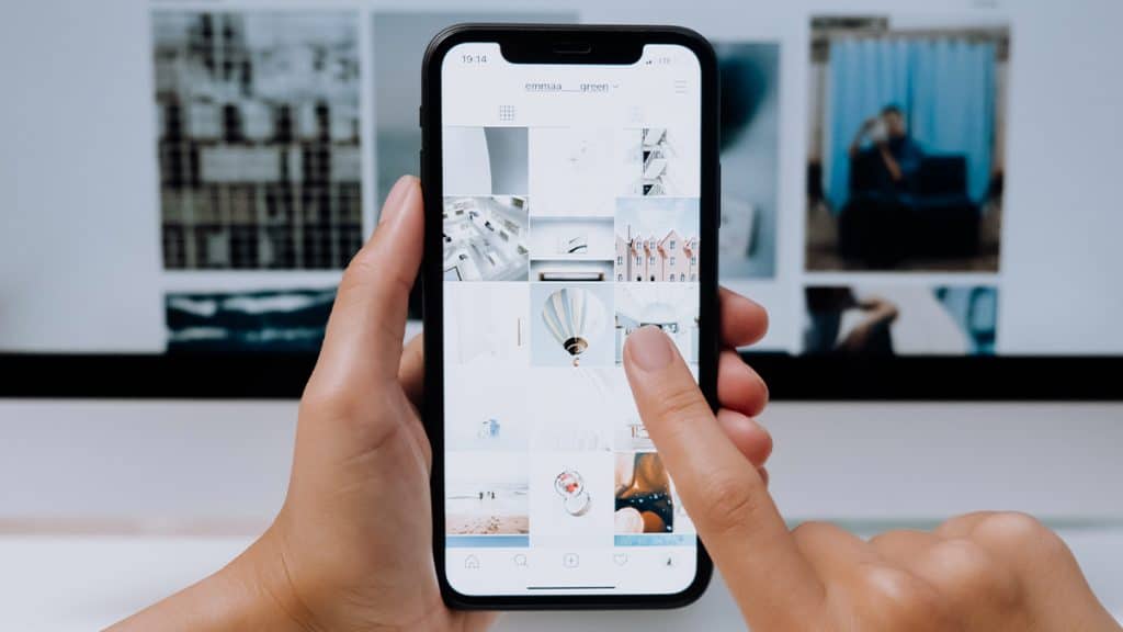 Pessoa tocando na tela de um iPhone com o dedo indicador enquanto segura o celular com a outra mão