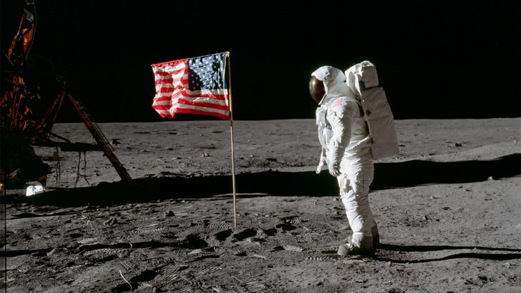Astronauta ao lado de bandeira dos Estados Unidos na Lua