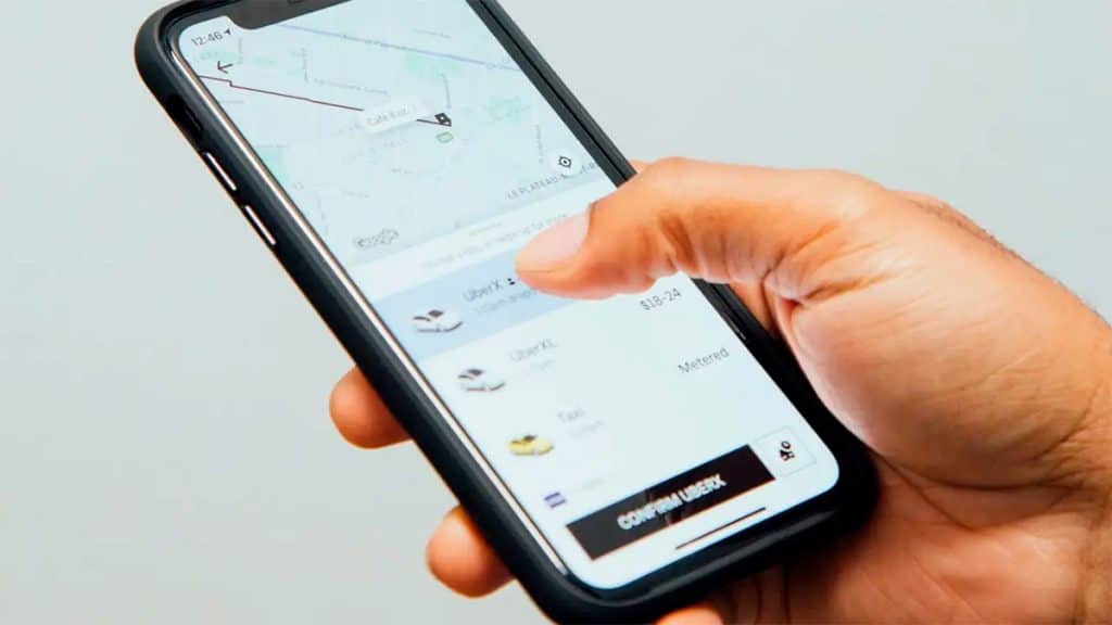 Pessoa segurando celular e prestes a confirmar viagem no Uber