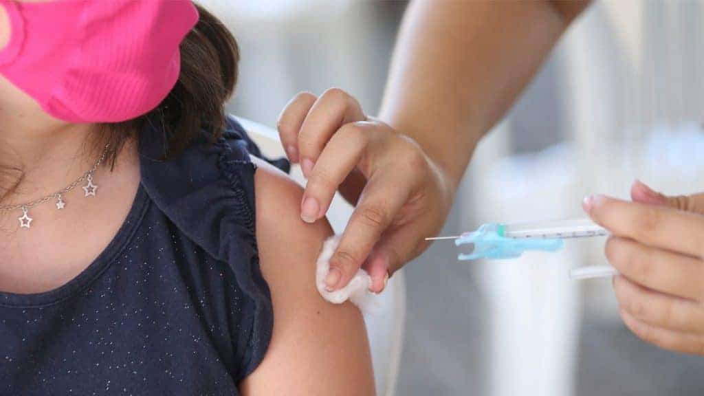 Enfermeira aplicando vacina contra Covid em braço de mulher