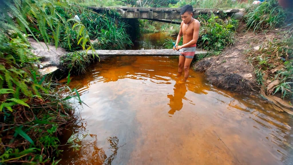 Habitante Yanomami de pé em córrego com água na altura das canelas