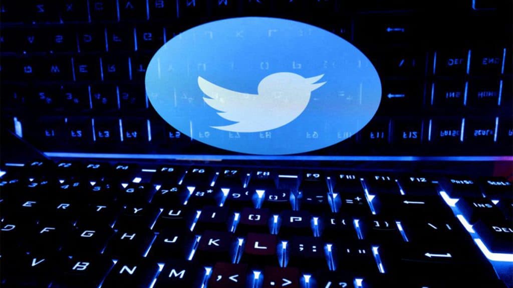 Notebook com logomarca do Twitter aberta e teclado acesso com luz azul