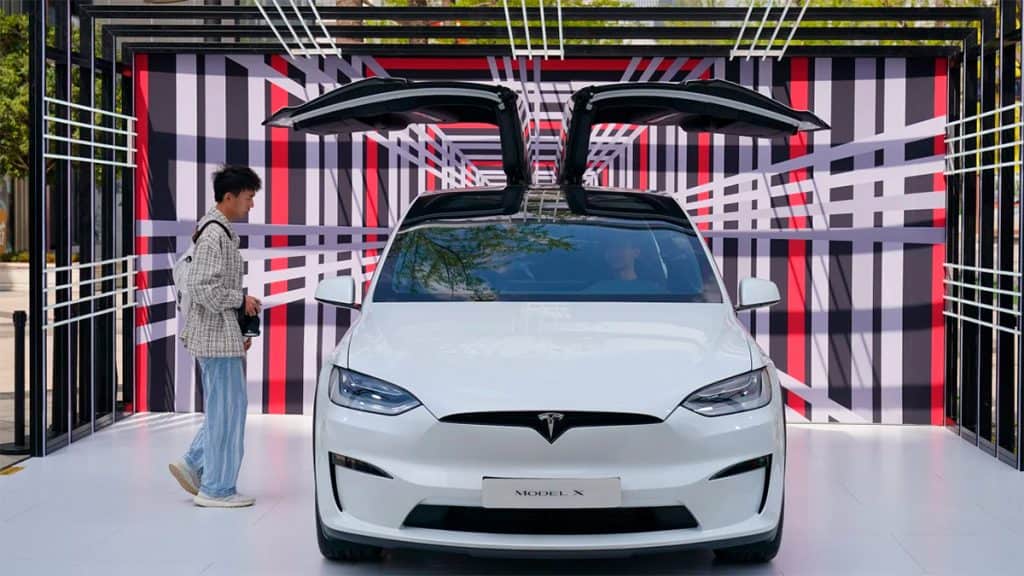 Carro da Tesla em exibição com um rapaz dentro e outro olhando