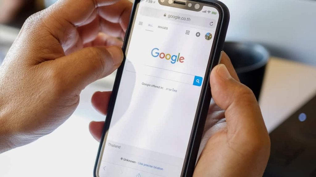 Pessoa segurando iPhone nas mãos com Google aberto em navegador