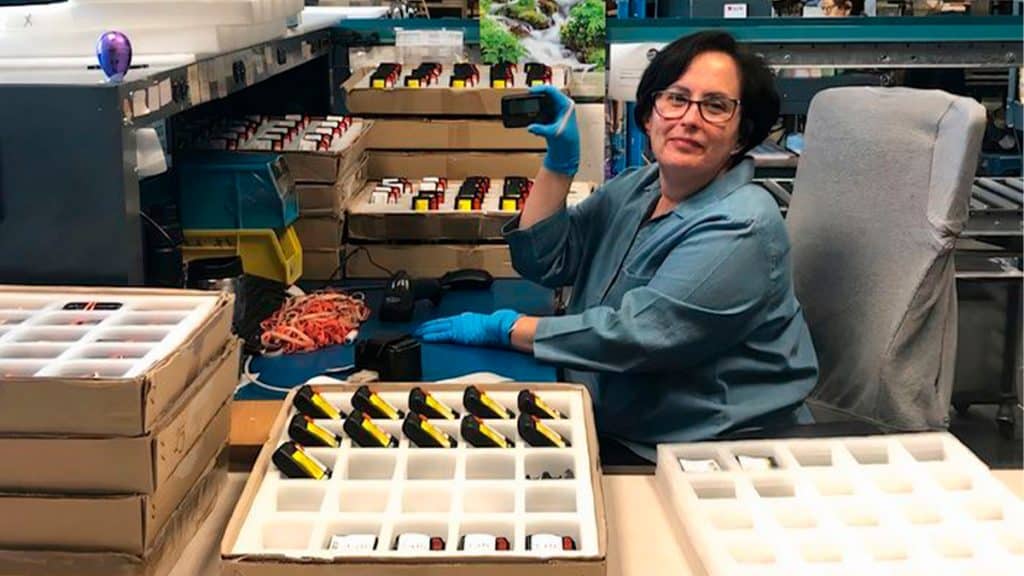 Mulher segurando pager em linha de embalagem de empresa