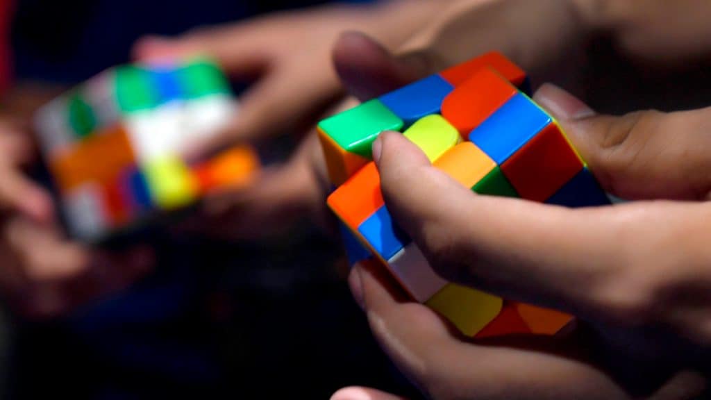 Duas pessoas competindo para ver quem resolver cubo mágico mais rápido