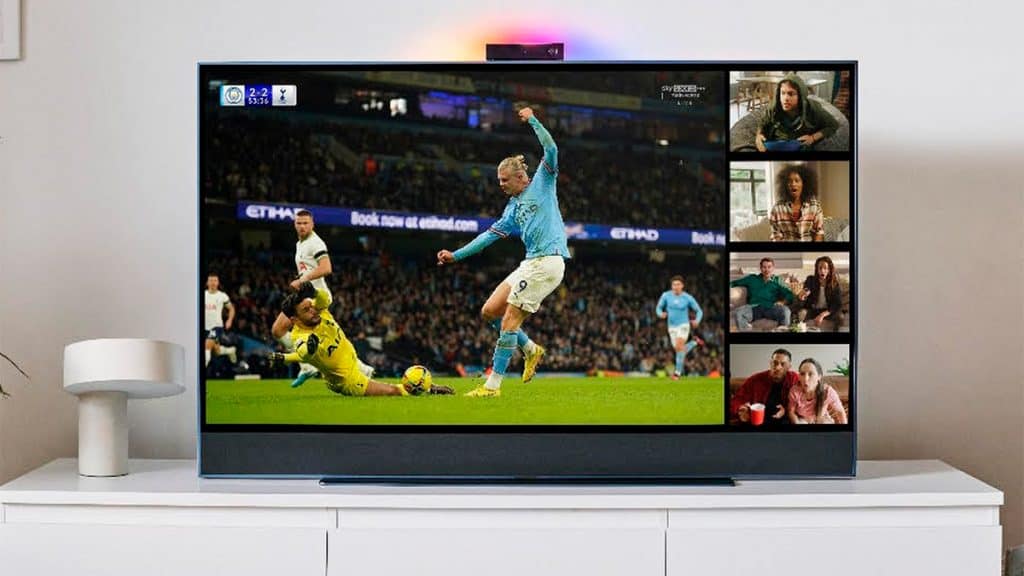 TV com webcam com jogo de futebol na tela e, no canto direito, três janelinhas de pessoas que estão assistindo juntas