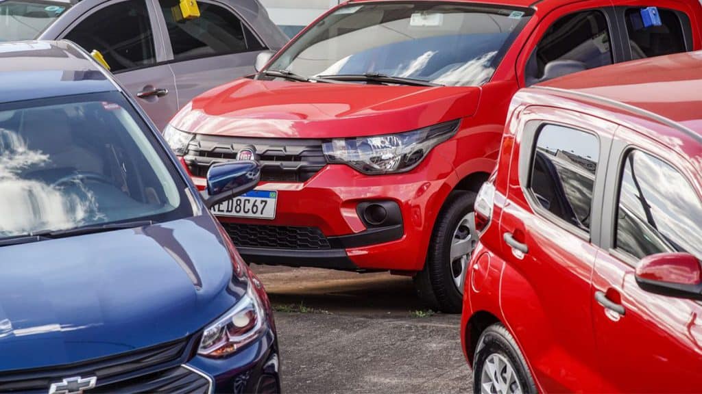 Modelos de carro popular de diversas marcas estacionados em pátio