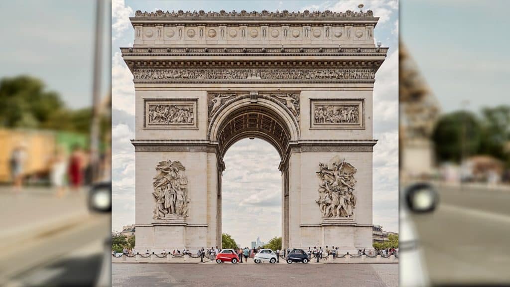 Três modelos de Microlino estacionados embaixo do Arco do Triunfo, em Paris, na França