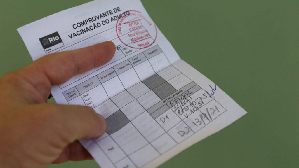 Pessoa segurando comprovante de vacinação
