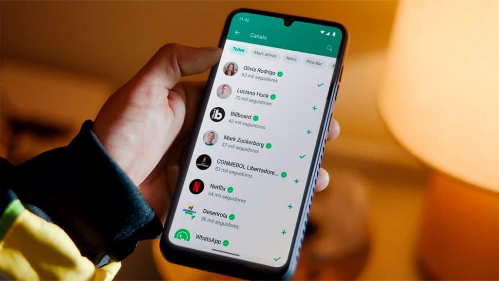 Montagem de homem segurando celular com lista de Canais do WhatsApp