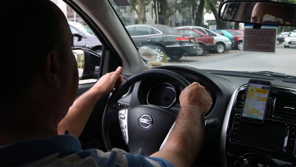 Motorista em carro prestando serviço para a Uber