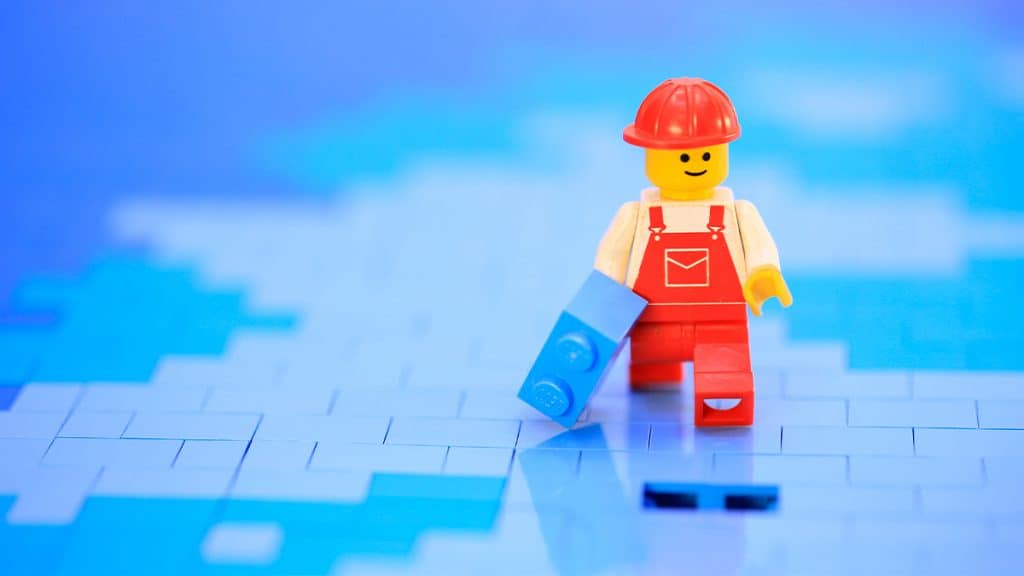 Trabalhador de Lego carregando pecinha em chão de Lego