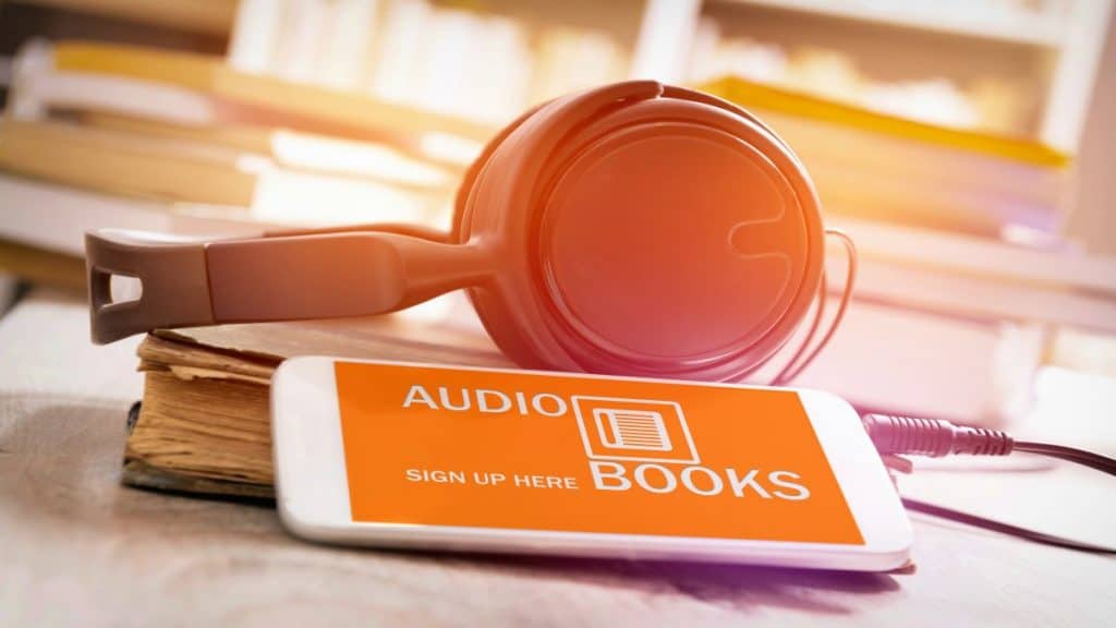 Fones de ouvido ao lado de celular com imagem escrito Audio Books