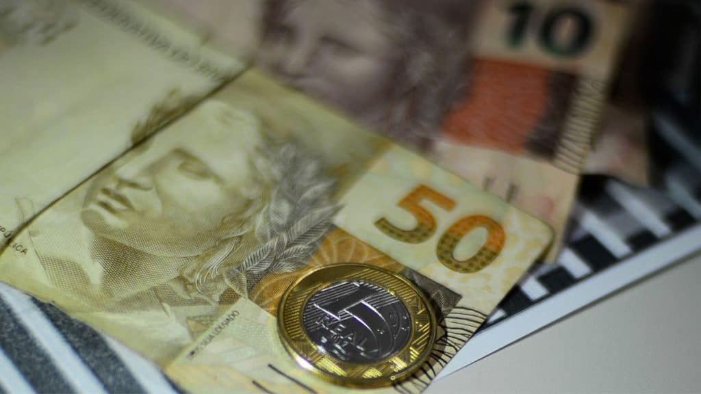 Dinheiro em notas e moedas sobre mesa