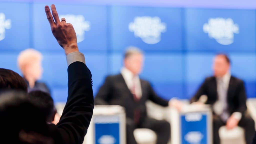 Pessoa com mão levantada em Fórum Econômico Mundial em Davos