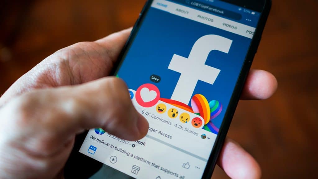 Pessoa dando "amei" no Facebook num iPhone