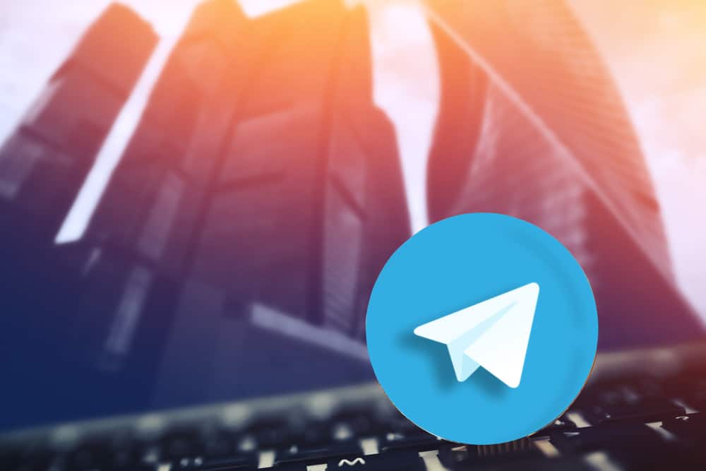símbolo do Telegram em primeiro plano e ao fundo prédios comerciais