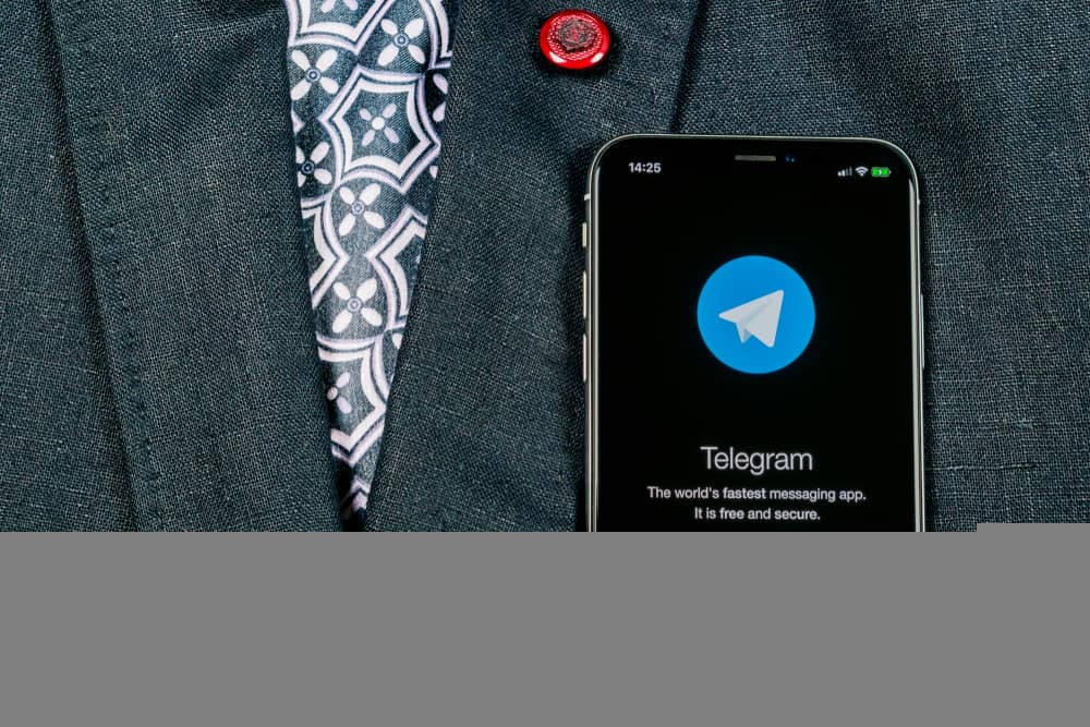 pessoa com terno e celular no bolso frontal com home e símbolo do Telegram