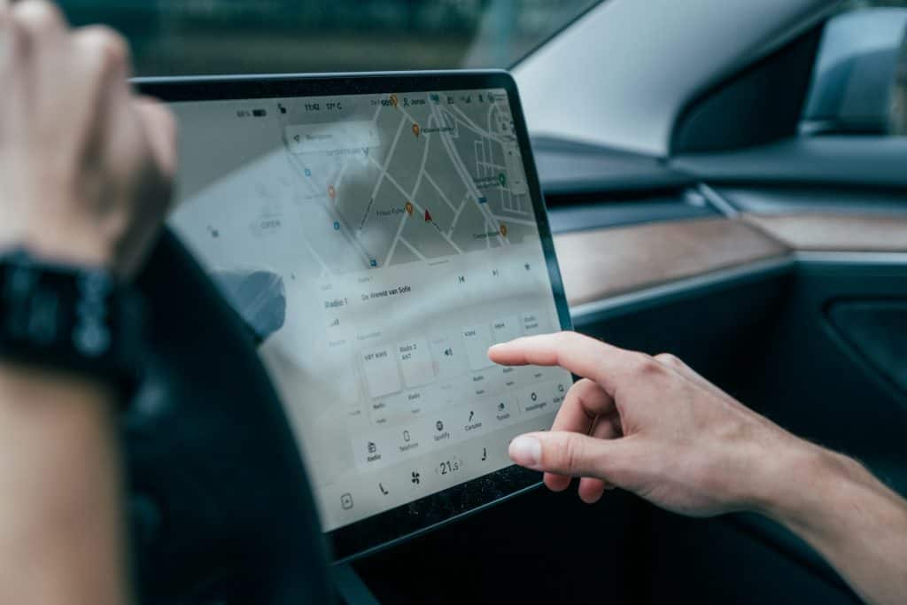 Motorista interagindo com tela instalada no carro via Jonas Leupe/Unsplash