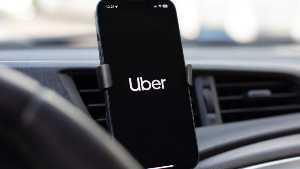 Smartphone preso ao console de um carro exibindo a logomarca da Uber