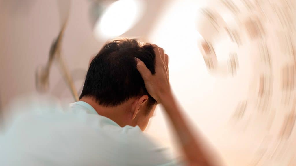 Homem na beira da cama com zumbido no ouvido