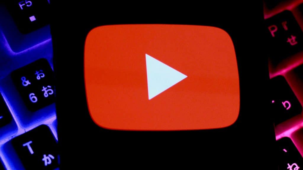 Celular com logotipo do YouTube na tela colocado sobre teclado mecânico gamer com luzes RGB acesas