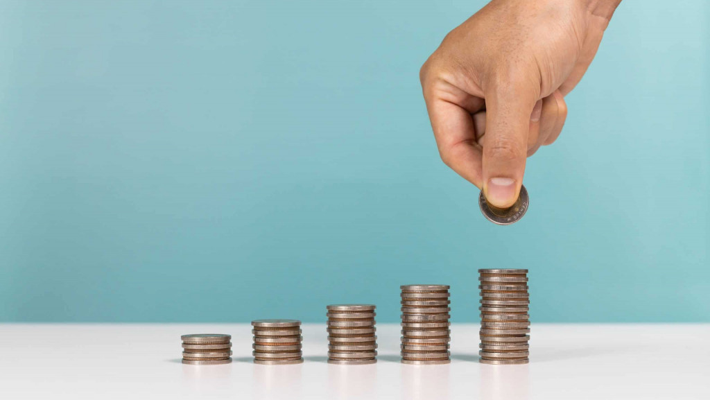 Pilhas de moedas e uma mão colocando outra em uma das pilhas