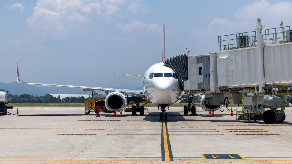 Avião em aeroporto com braço acoplado à sua porta