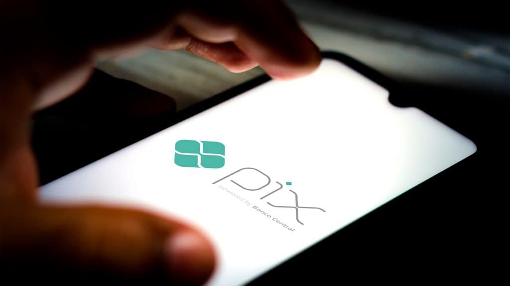 Pessoa quase tocando em tela de celular com logotipo no PIX