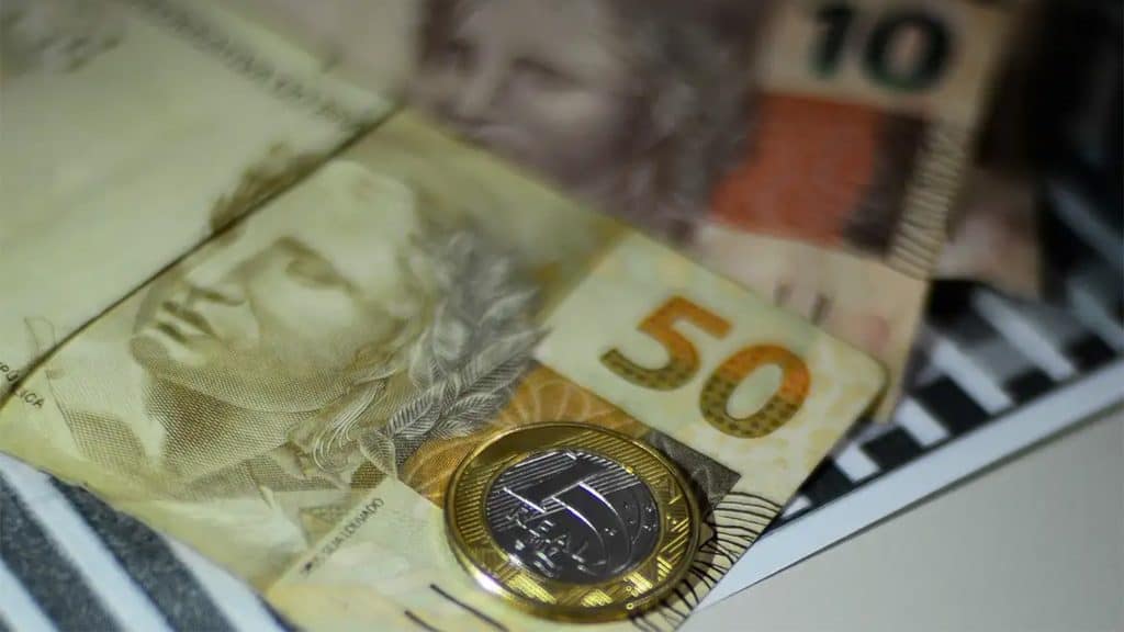Notas e moeda de Real colocadas uma sobre as outras