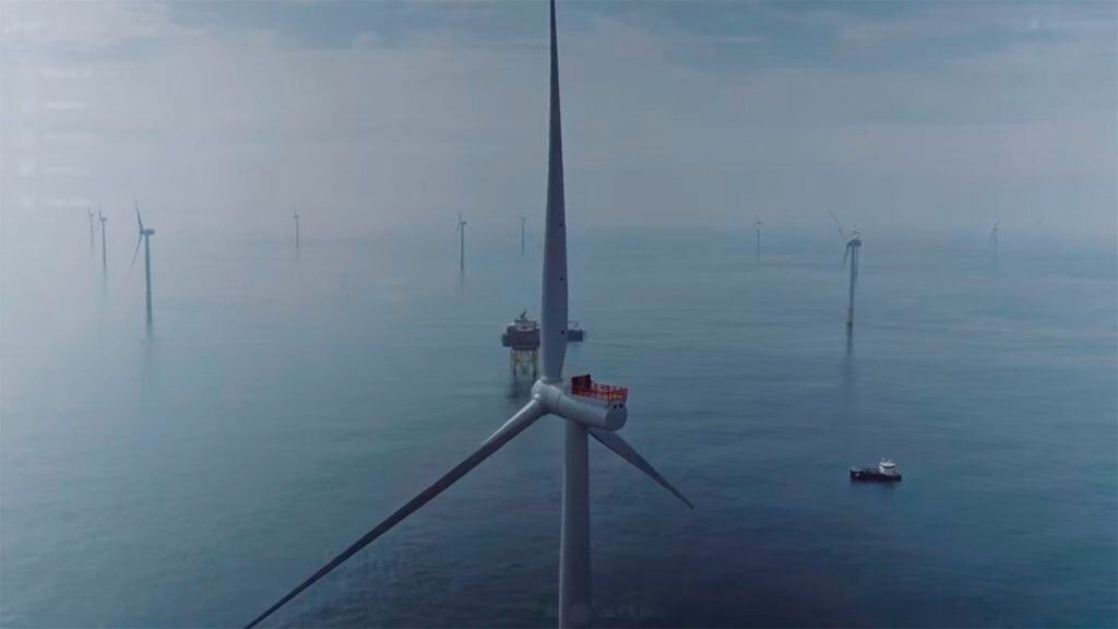 Visão aérea de fazenda de turbinas eólicas com um dos navios elétricos da Parkwind a deriva no oceano