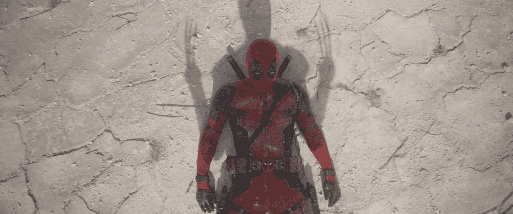 Cena do filme Deadpool & Wolverine. Ela mostra o personagem Deadpool deitado no chão. Por cima dele, vemos a sombra das garras de Wolverine.