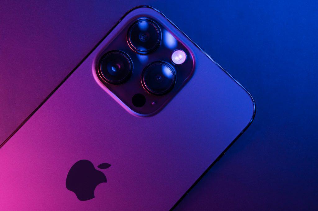 Close-up do iPhone 14 Pro Max Space Black isolado em fundo preto iluminado por luzes azuis e rosas