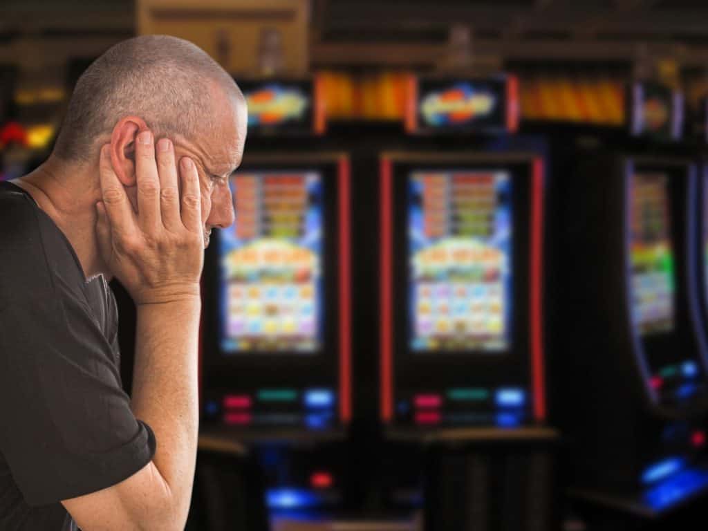 homem triste em frente a máquinas de jogos caça-nível