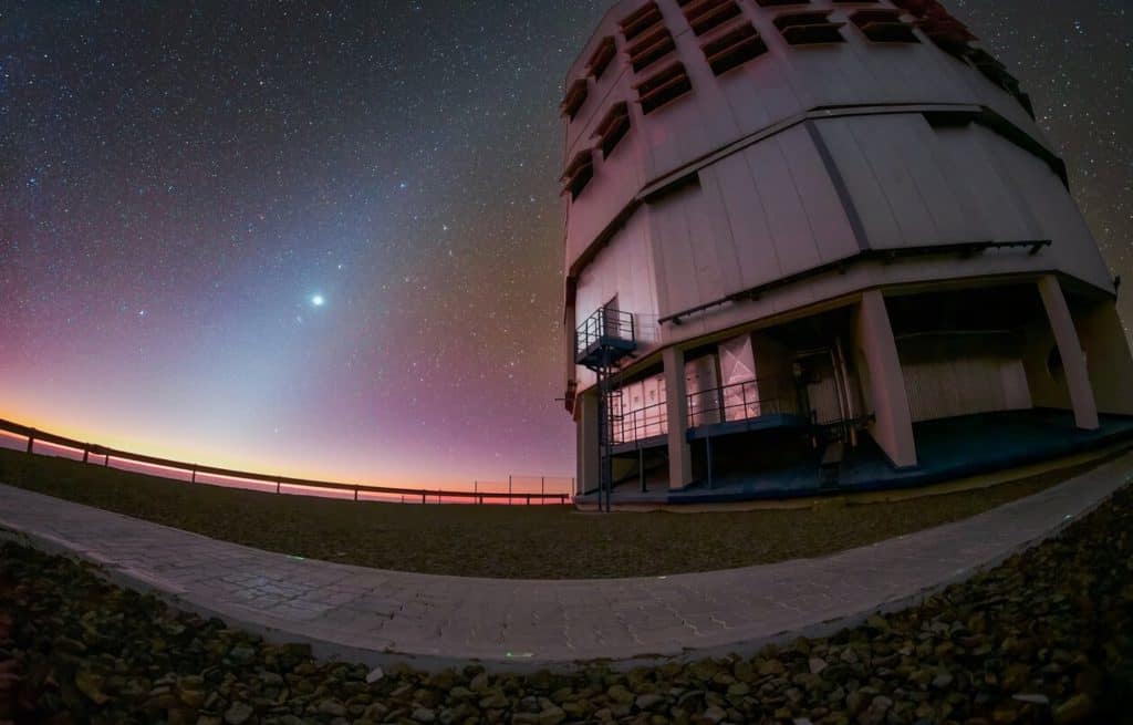 Imagem mostra a luz zodiacal captirada por um dos telescópios da instalação VLT, um observatório astronômico localizado no Chile. À esquerda da imagem é possível ver um céu estrelado e uma luz brilhante no centro