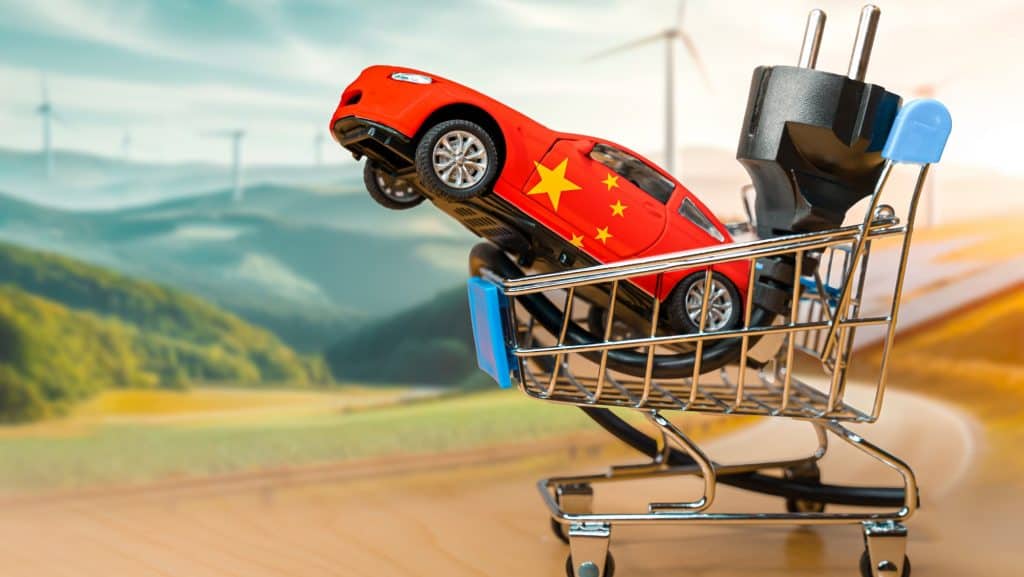 Carro elétrico com a bandeira da China e plugue elétrico dentro de um pequeno carrinho de compras.