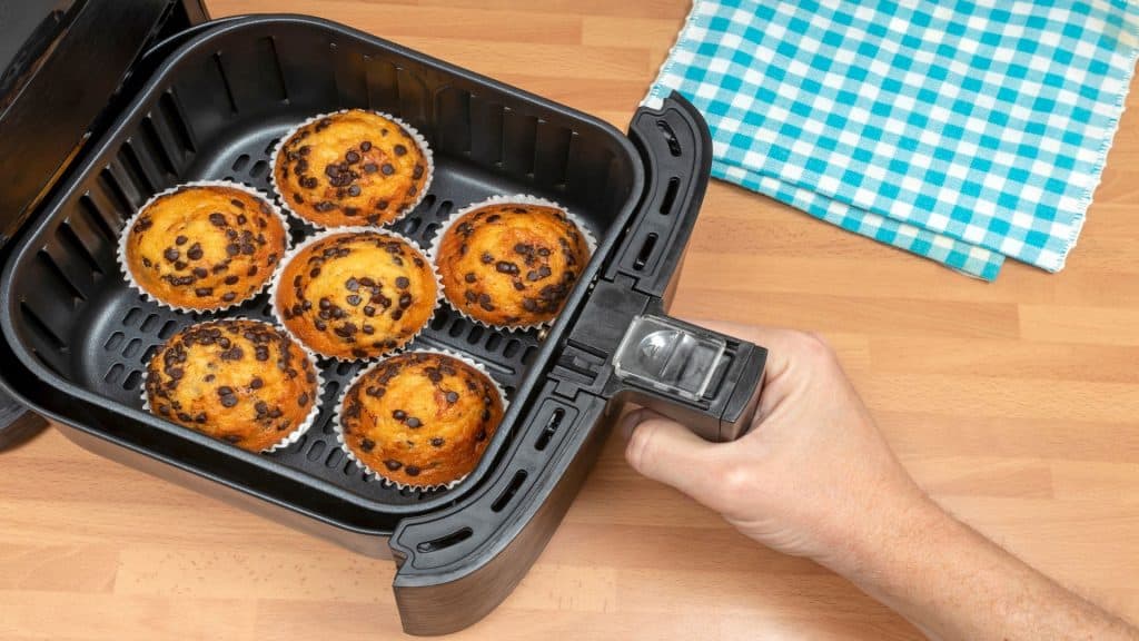 ASSANDO MUFFINS OU CUPCAKES CASEIROS COM GOTAS DE CHOCOLATE NA AIR FRYER NA COZINHA. VISTA DE CIMA.
