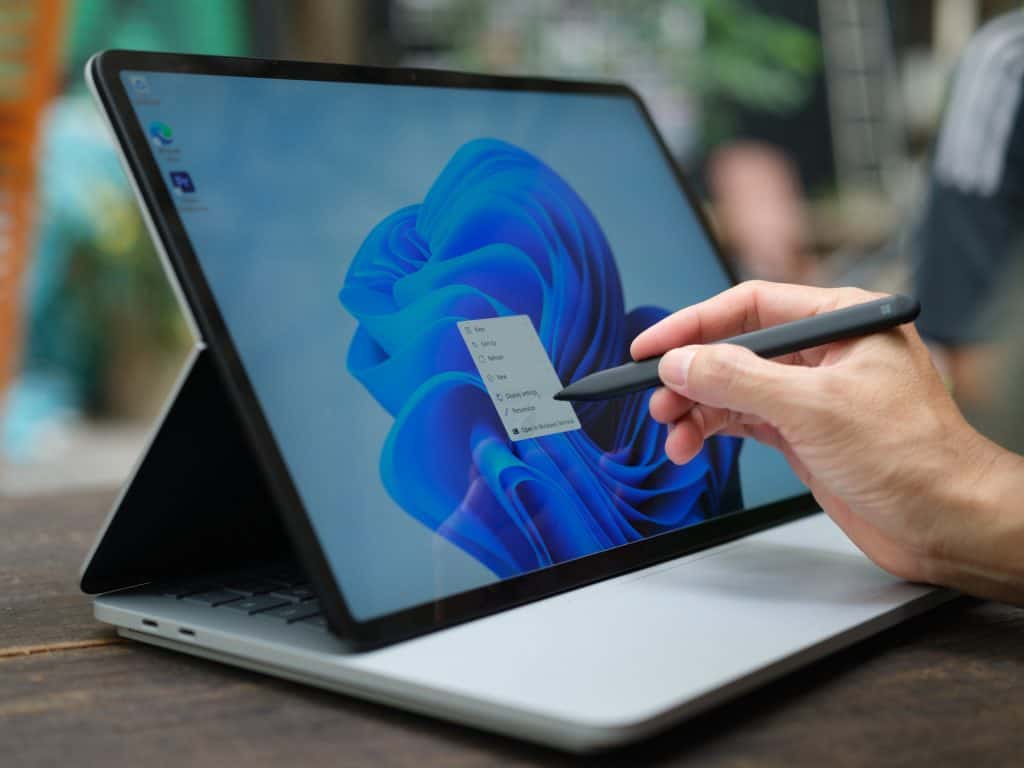Mão tocando, com uma caneta, a tela de um Microsoft Surface