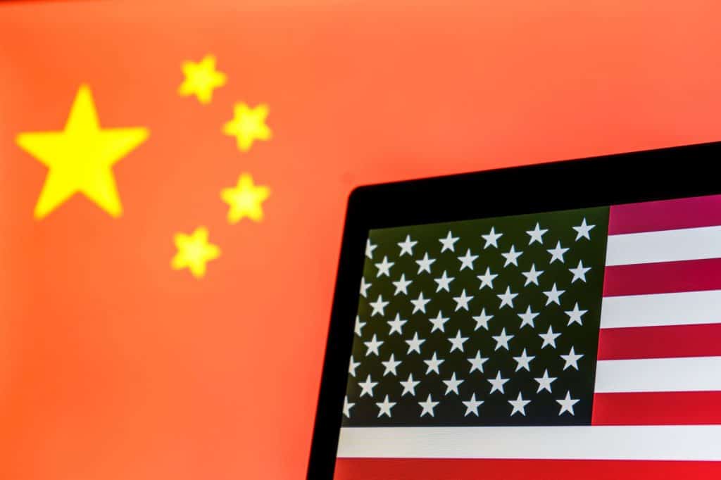 Bandeira da China ao fundo; à frente, bandeira dos EUA em tela de notebook