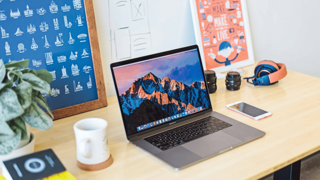 imagem ilustra um macbook em cima de uma mesa em um home office